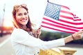 Young patriot woman with toothy smile stretching USA flag in sunset