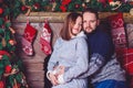 Happy young people give each other gifts by fireplace near the Christmas tree. Royalty Free Stock Photo