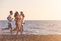 Happy young people group have fun white running and jumping on beach at sunset time Royalty Free Stock Photo