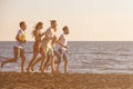 Happy young people group have fun white running and jumping on beach at sunset time Royalty Free Stock Photo