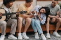 Happy young people with guitar and dog spending fun time near RV, singing songs, camping together on summer vacation Royalty Free Stock Photo