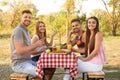 Happy young people having picnic at table