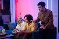 Happy young people playing video games on console while sitting on couch in front of tv. Man advice his friend in a game Royalty Free Stock Photo