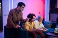 Happy young people playing video games on console while sitting on couch in front of tv. Man advice his friend in a game Royalty Free Stock Photo