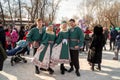 Happy young people in Russian ethnic costumes stand among the crowd of people at the Happy Winter holiday in the city park