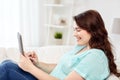 Happy young plus size woman with tablet pc at home