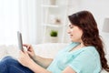 Happy young plus size woman with tablet pc at home