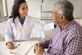 Happy young practitioner woman giving comfort to older Indian patient