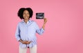 Happy young pregnant african american curly woman in casual with big belly show ultrasound shot