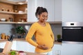 Happy young pregnant african american woman touching her big belly and feeling baby move Royalty Free Stock Photo