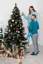 Happy young pregnant couple decorating Christmas tree. Smiling Man and Woman together Celebrating Christmas or New Year Royalty Free Stock Photo