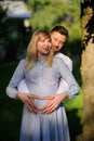 Happy and young pregnant couple hugging outdoor