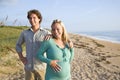 Happy young pregnant couple standing on beach Royalty Free Stock Photo