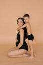 A happy young pregnant mother with her son on a beige background. The concept of a happy European or American family Royalty Free Stock Photo