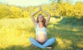 Happy young pregnant relaxed woman doing yoga sitting on grass in summer park Royalty Free Stock Photo