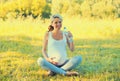 Happy young pregnant woman drinking water from plastic bottle sitting on the grass in sunny summer park Royalty Free Stock Photo