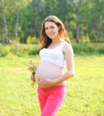 Happy young pregnant woman with flowers outdoors in summer Royalty Free Stock Photo