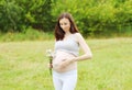 Happy young pregnant woman with flowers outdoors in summer Royalty Free Stock Photo