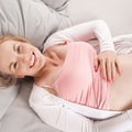 Happy young pregnant woman lies in bed and dreams of her future child. Top view