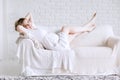 Happy young pregnant woman lying on sofa in bright living room Royalty Free Stock Photo