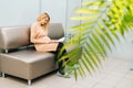 Happy young pregnant woman is sitting in hallway of hospital waiting to see gynecologist. Royalty Free Stock Photo