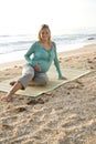 Happy young pregnant woman sitting on mat at beach Royalty Free Stock Photo