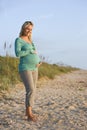 Happy young pregnant woman standing at beach Royalty Free Stock Photo