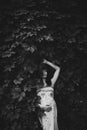 Happy young pregnant woman in summer park among set of green leaves. Stylish black and white photo