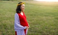 Happy young pregnant woman walking in the fresh air in the afternoon in a red dress Royalty Free Stock Photo