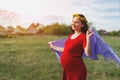 Happy young pregnant woman walking in the fresh air in the afternoon in a red dress Royalty Free Stock Photo