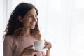 Happy young pretty lady drinking hot tea, looking at window. Royalty Free Stock Photo