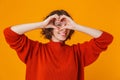 Happy young pretty woman posing isolated over yellow wall background showing heart gesture Royalty Free Stock Photo