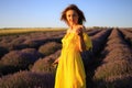 Happy young pretty woman walks at sunset in a lavender field with a bouquet in her hands and enjoys solitude with nature
