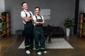 happy young professional cleaners standing with crossed arms and smiling