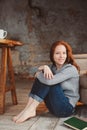 Happy young readhead woman drinking hot coffee or tea at home. Calm and cozy weekend in winter