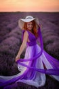 Happy red-haired woman in luxurious dress standing in lavender field at sunset Royalty Free Stock Photo