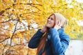 happy young red haired woman wearing coat and beanie smiling and looking at a tree. walking in an autumn forest. local Royalty Free Stock Photo