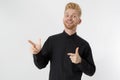 Happy young redhead guy with red stylish beard isolated. Man pointing copy space for advertising. Male in black shirt, trend Royalty Free Stock Photo