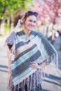 Happy young redhead woman in poncho at spring looking at camera