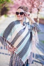 Happy young redhead woman in poncho at spring holding sunglasses