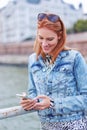 Happy young redhead woman reading message on smartphone at riverbank Royalty Free Stock Photo