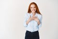 Happy young redhead woman thanking you, holding hands on chest and smiling, looking grateful at camera, white background