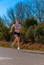 A happy young runner girl, dressed in running shorts and a white top, running in mid-air with style and perfect technical Royalty Free Stock Photo