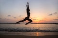 Happy young slender woman jumping and having fun at sunset on the beach by the sea Royalty Free Stock Photo