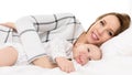 Happy young smiling mother and her baby son lying on a bed together. Mother and newborn child portrait. Royalty Free Stock Photo