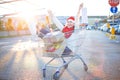 Happy young smiling woman sitting in shopping cart with a lot of gift boxes and two shopping bags in her hands Royalty Free Stock Photo