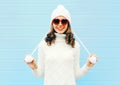 Happy young smiling woman wearing a heart shape sunglasses, knitted hat, sweater over blue Royalty Free Stock Photo