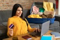 Happy young spanish lady using credit card and laptop, booking abroad trip or making hotel reservation on web Royalty Free Stock Photo