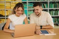 Happy young students of boy and girl preparing in library for exam in university. Two people study. Back view of books Royalty Free Stock Photo