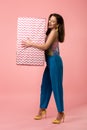 Young stylish disco girl holding big gift box on pink